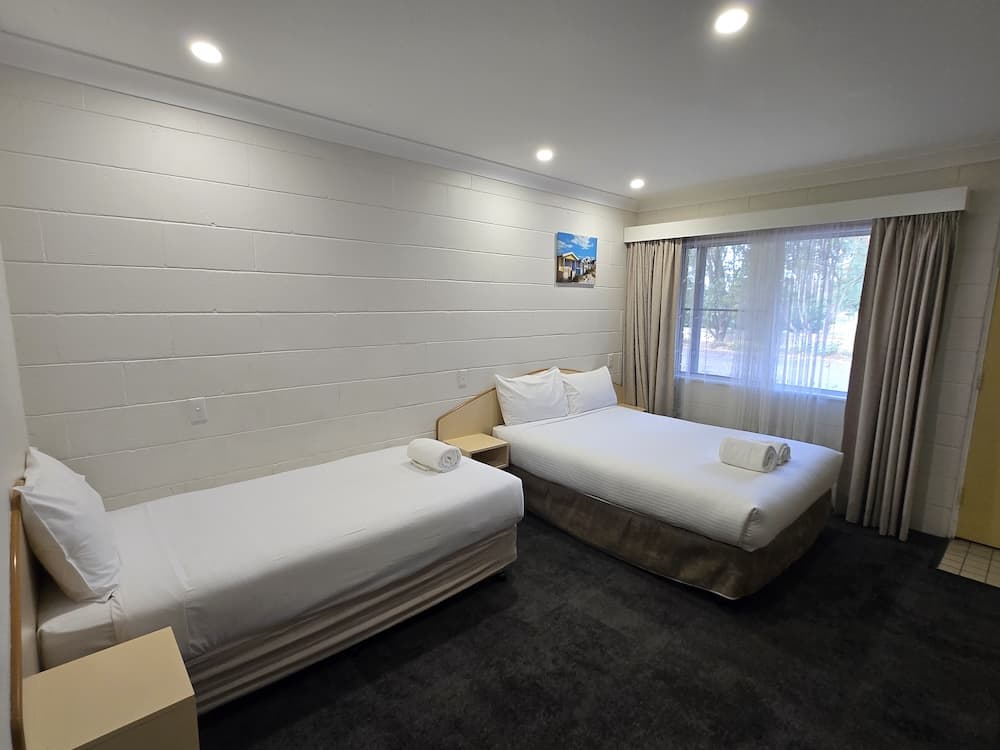 twin room home with textured white walls, a dark carpet, and a large window with beige curtains.